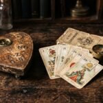 An antique wooden planchette, a worn Lenormand tarot deck, and a brass magnifying loupe on a dark wood table