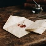 A broken wax seal on an antique billet envelope, candlelight, quill and ink beside old books