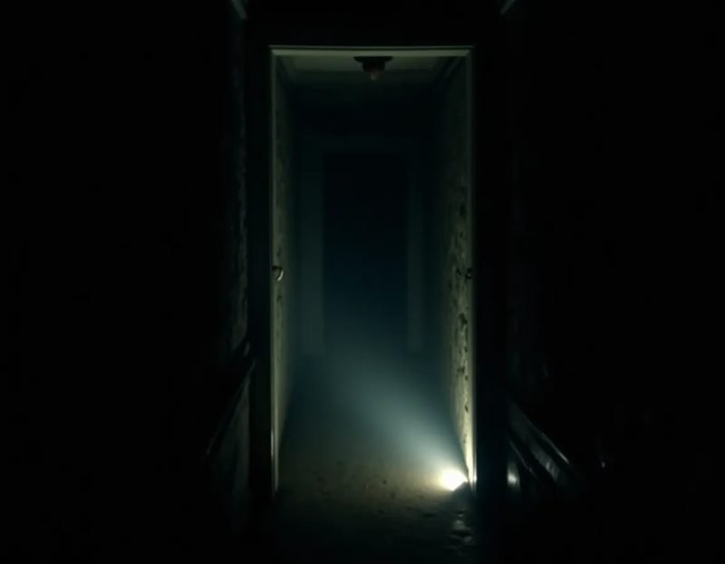 a dark hallway lit only by a handheld flashlight beam